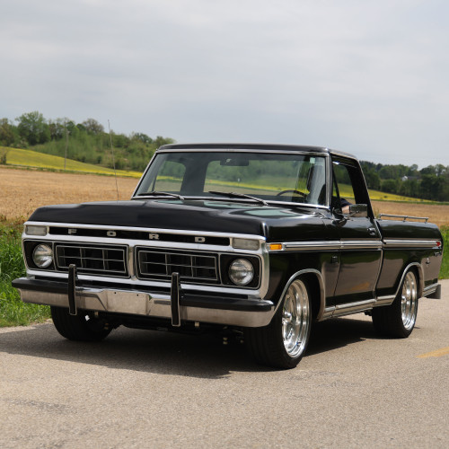 Black F100 on Ridetech air suspension and chrome wheels driving against an agricultural backdrop